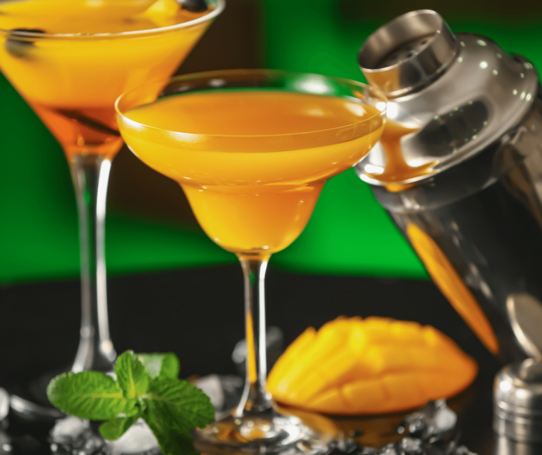 Indischer Aperitif Mango Sekt in Cocktailgläsern mit Minze und Mangostücken garniert