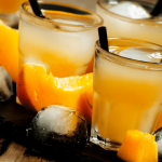Mango Wodka in Long Drink Gläsern mit schwarzen Strohhalmen, Eiswürfeln und Mangowürfeln