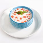 Indischer Joghurt Salat mit Tomate, in einem blauen Schüsselchen mit Minze garniert