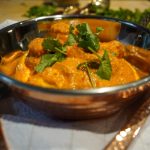 Butter Chicken | Murgh Makhani mit grünem Koriander garniert in einem Kupferschälchen angerichtet. Bereit, um gegessen zu werden.