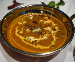 Dal Makhani in einer Kupferschale angerichtet mit Sahne-Swirls und frischen Methi-Blättern und etwas zerlassner Butter in der Sauce.