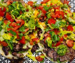 Foto von zwei oben offenen Naans mit Smashburger-Füllung: TOmaten, Koriander, Salatherzen und Bärlauchpesto auf einem Rindfleisch-Kidneybohnen-Pesto