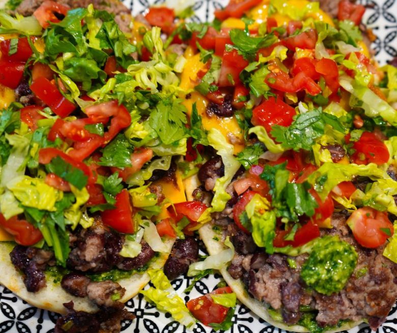 Foto von zwei oben offenen Naans mit Smashburger-Füllung: TOmaten, Koriander, Salatherzen und Bärlauchpesto auf einem Rindfleisch-Kidneybohnen-Pesto