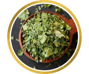 Kasuri Methi auf einem Holzkochlöffel angerichtet. Die grünen, getrockneten Blätter des Bockshornklees liegen locker auf dem Löffel.