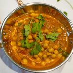 Cremiges Kichererbsen-Curry in einer Kupferschale angerichtet und mit Koriander garniert.