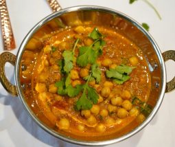 Cremiges Kichererbsen-Curry in einer Kupferschale angerichtet und mit Koriander garniert.