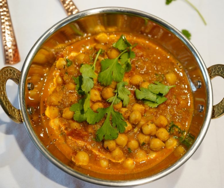 Cremiges Kichererbsen-Curry in einer Kupferschale angerichtet und mit Koriander garniert.