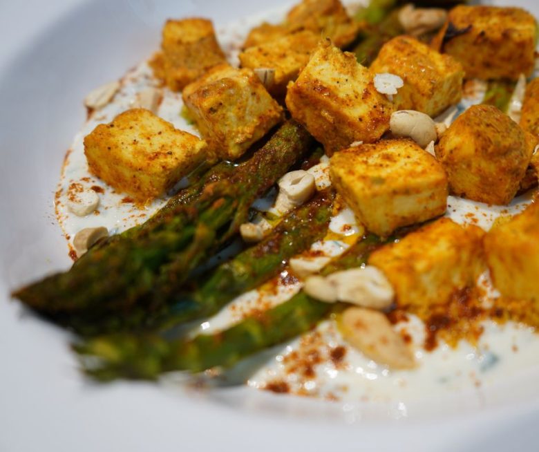 Tandoori-Spargel aus dem Ofen mit Paneer Tikka & Zitronen-Joghurt angerichtet auf einem großen, weißen Teller